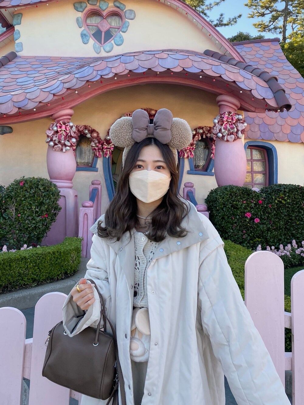 ベージュ系のショルダーバッグ、ホワイト系のダウンジャケット/コート、ホワイト系のニット/セーターを着用したレディースの冬コーディネートの4枚目の写真