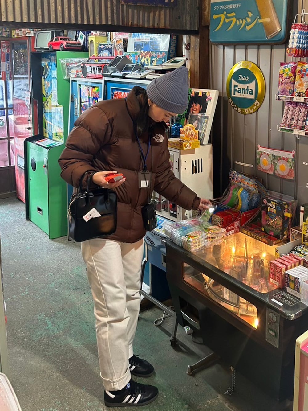 ブラック系のスニーカー、ブラウン系のダウンジャケット/コート、ホワイト系のデニムパンツを着用したレディースの冬コーディネートの2枚目の写真