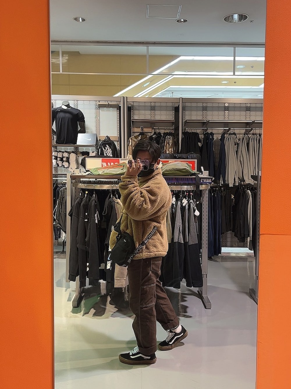 ブラウン系のデニムパンツ、ブラック系のスニーカー、ブラック系のショルダーバッグを着用したメンズの冬コーディネートの2枚目の写真