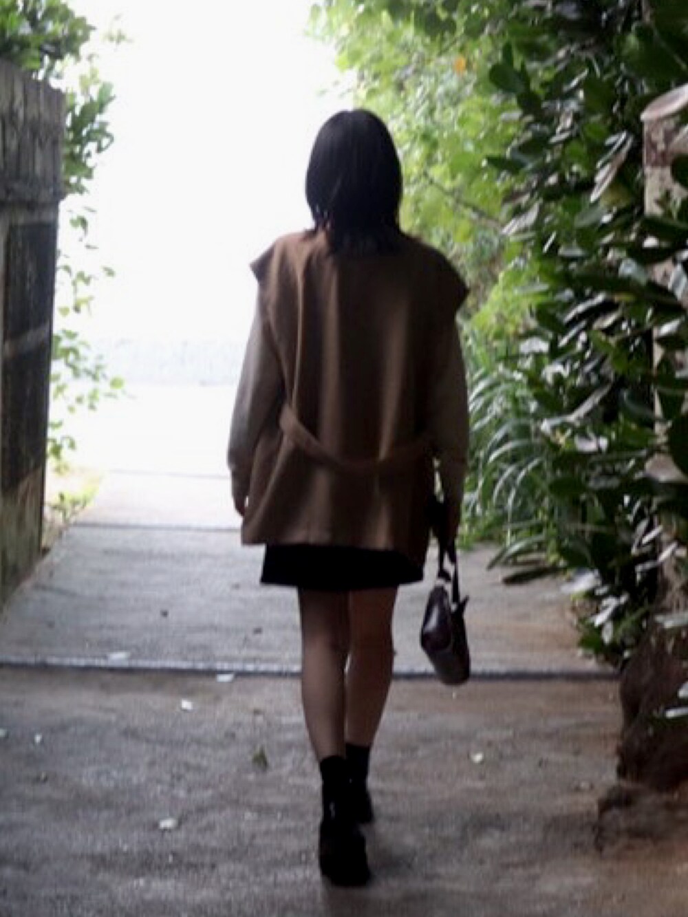 ブラック系のブーツ、ベージュ系のTシャツ/カットソー、ブラウン系のショルダーバッグを着用したレディースの冬コーディネートの2枚目の写真