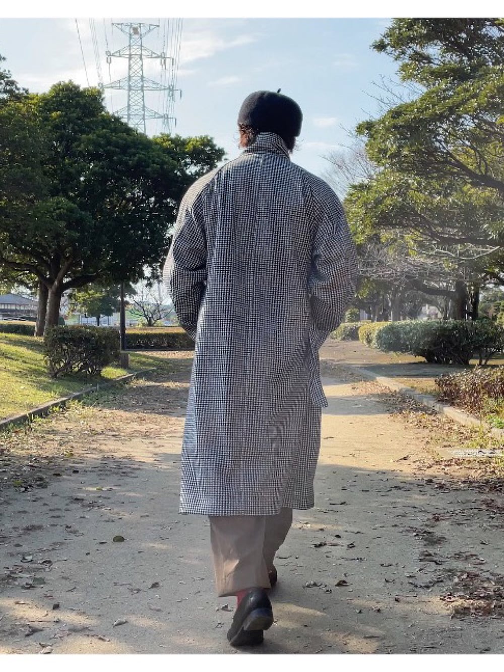 イエロー系のニット/セーター、ブラック系のチェスターコート、グリーン系のスラックスを着用したメンズの冬コーディネートの2枚目の写真