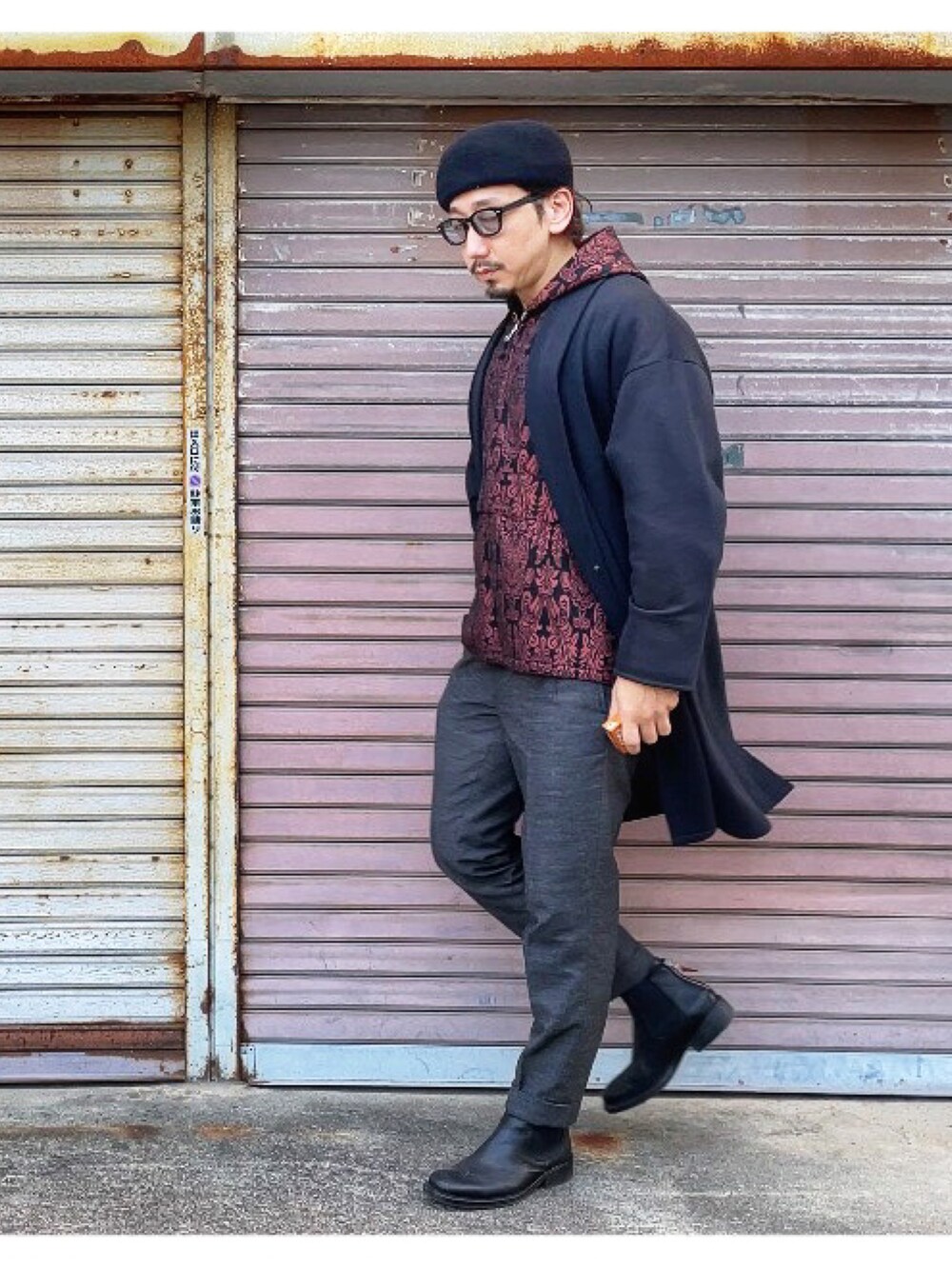 レッド系のパーカー、グレー系のスラックス、ブラック系のその他アウターを着用したメンズの冬コーディネートの2枚目の写真