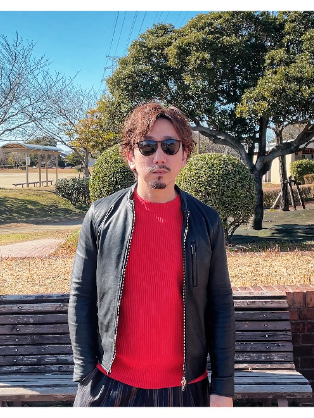ブラック系のライダースジャケット、ブラック系のスラックス、レッド系のニット/セーターを着用したメンズの冬コーディネートの3枚目の写真