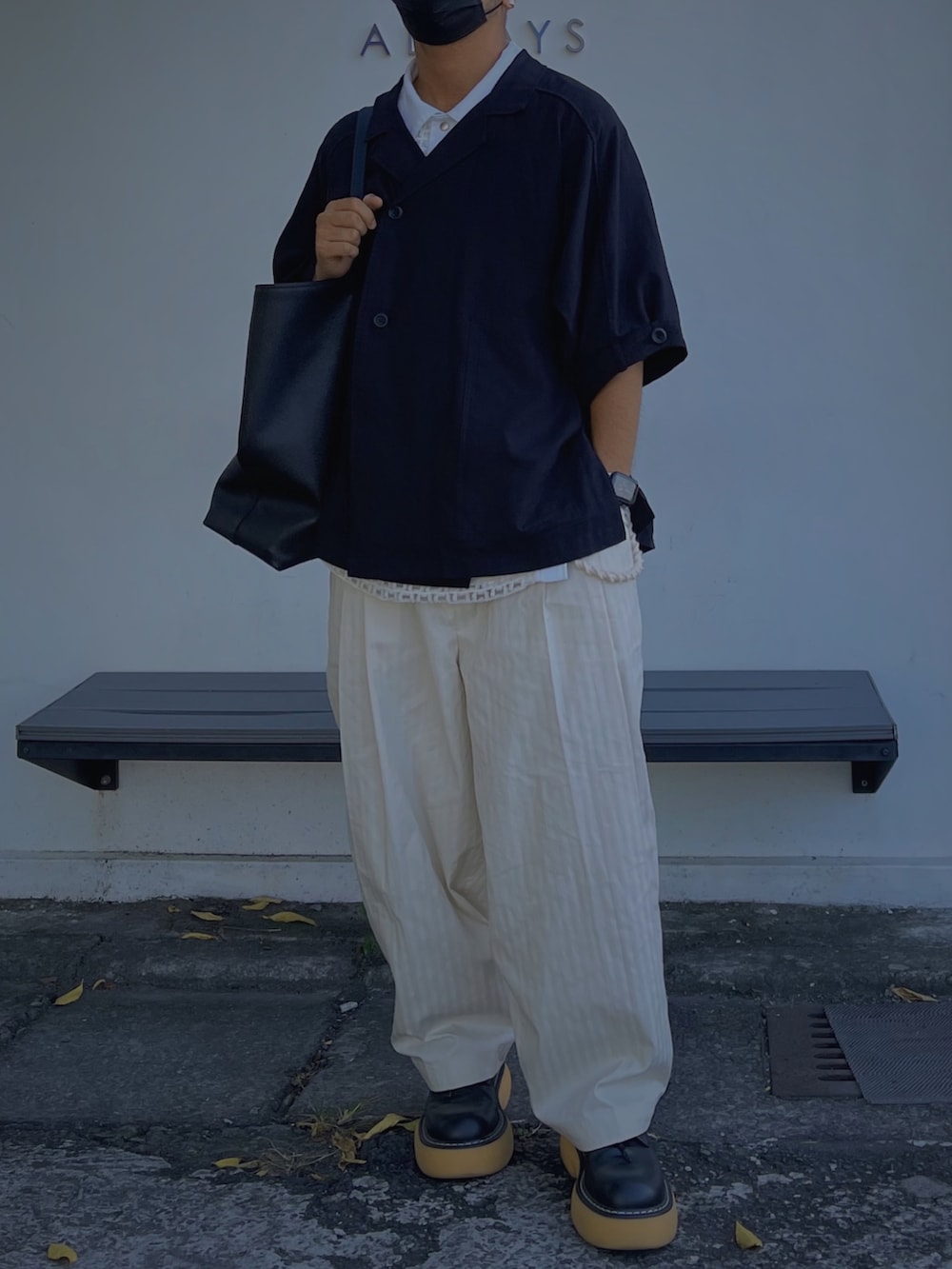 ブラック系のトートバッグ、ブラック系のトップス、ホワイト系のパンツを着用したメンズの秋コーディネートの3枚目の写真