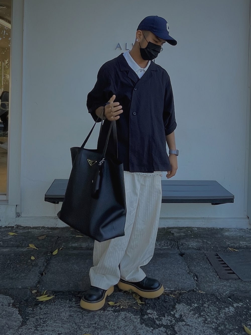 ブラック系のトートバッグ、ブラック系のトップス、ホワイト系のパンツを着用したメンズの秋コーディネートの2枚目の写真