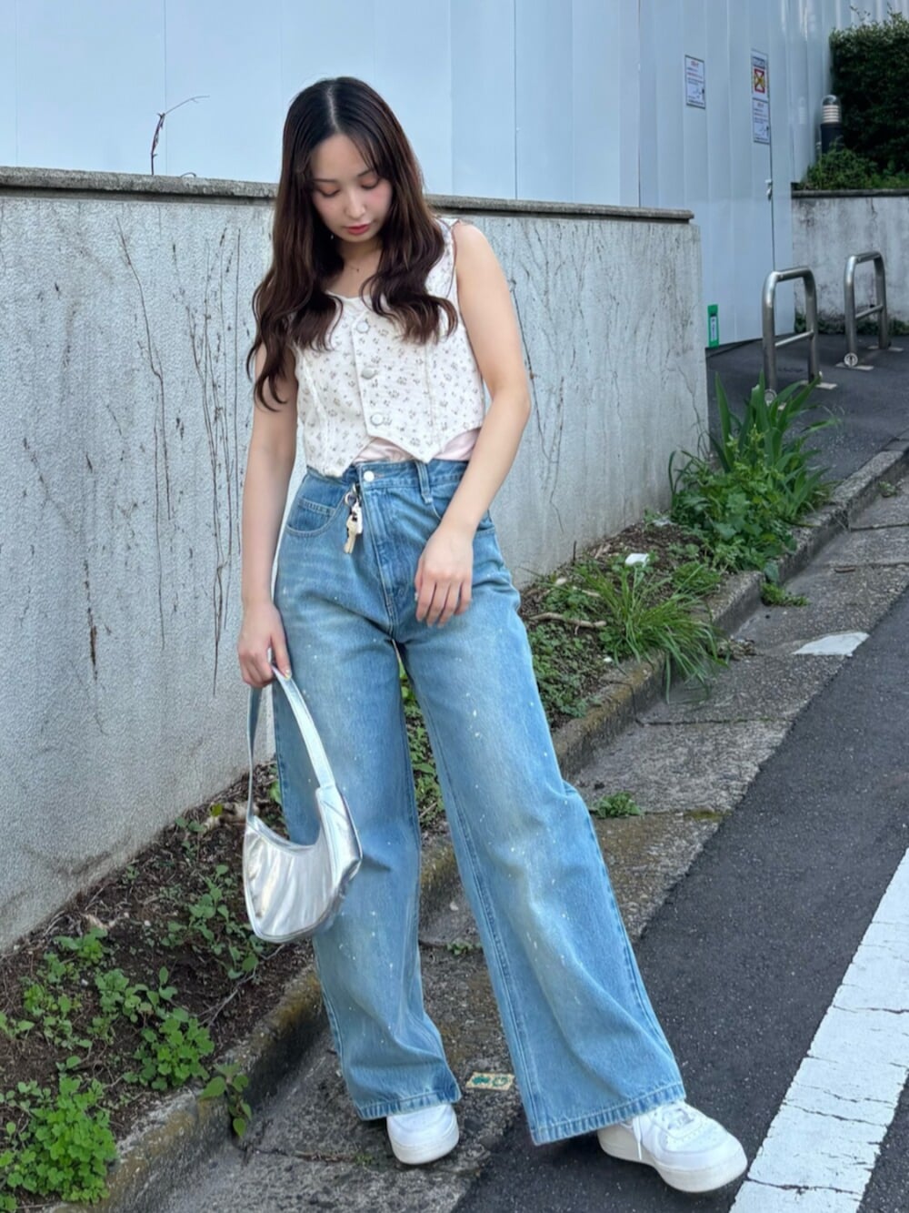 ピンク系のベスト、ピンク系のキャミソール、ブルー系のデニムパンツを着用したレディースの春コーディネートの2枚目の写真