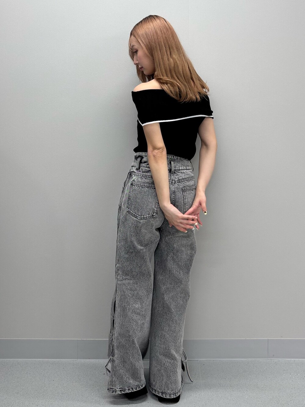 ブルー系のデニムパンツ、ブラック系のニット/セーター、ホワイト系のサンダルを着用したレディースの春コーディネートの4枚目の写真