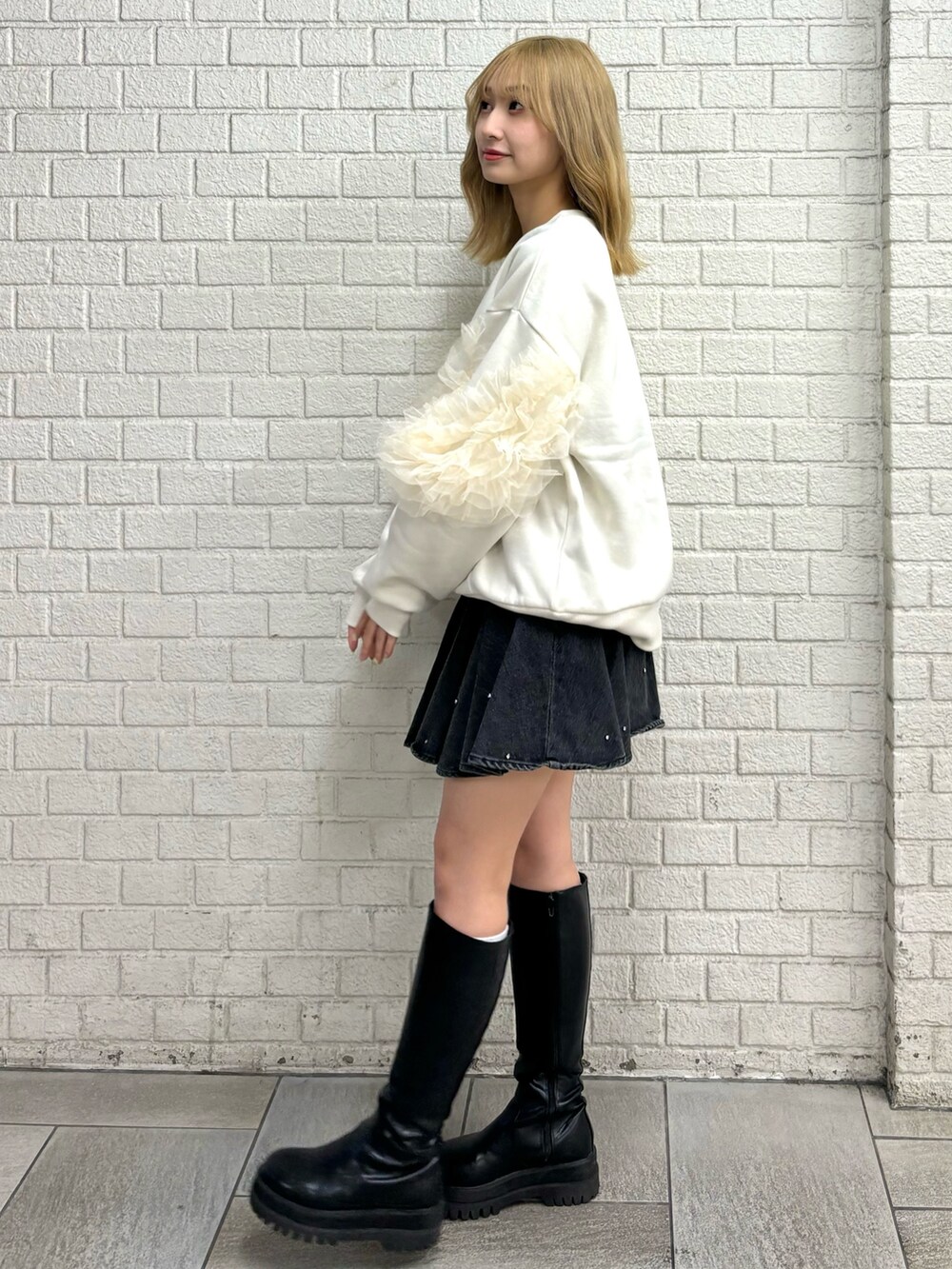 ホワイト系のスウェット、ブラック系のブーツ、ブルー系のスカートを着用したレディースの秋コーディネートの2枚目の写真