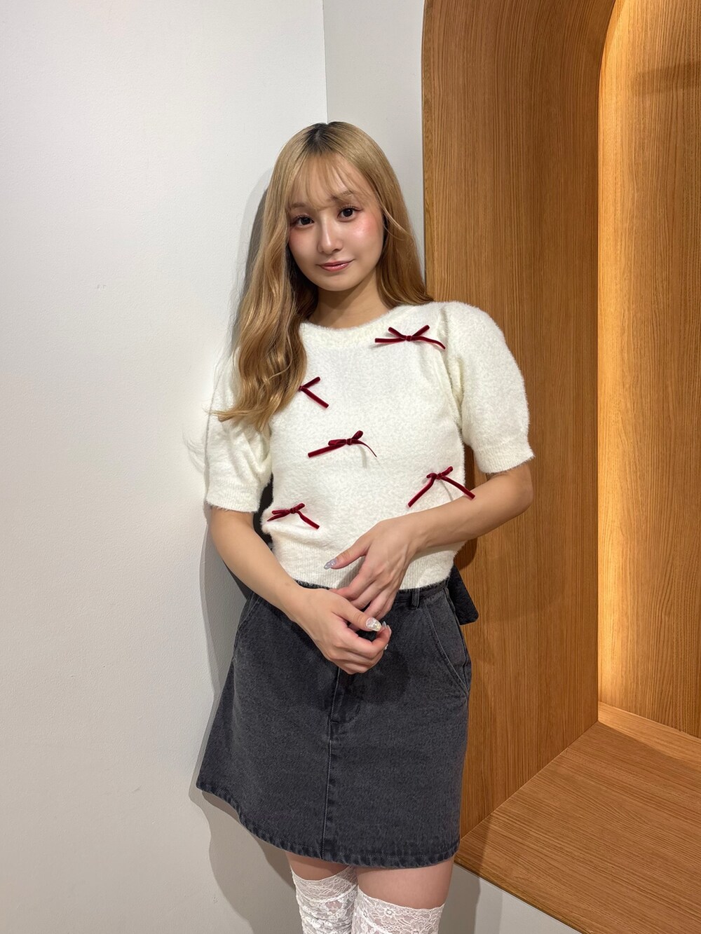 ブラック系のデニムスカート、ホワイト系のニット/セーター、ブラウン系のブーツを着用したレディースの秋コーディネートの5枚目の写真