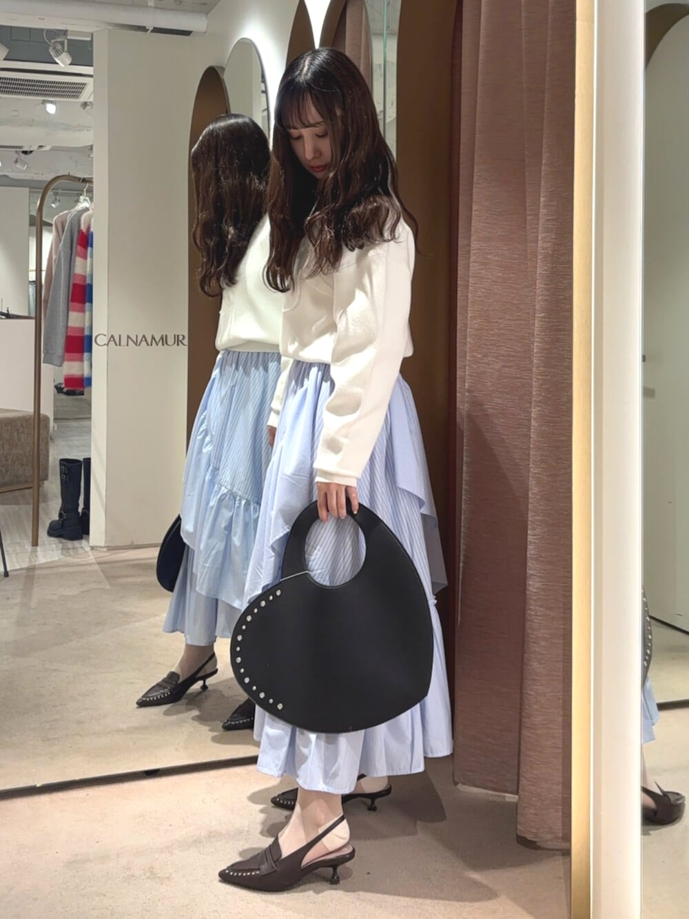 ブラウン系のサンダル、ホワイト系のニット/セーター、ブルー系のスカートを着用したレディースの春コーディネートの2枚目の写真