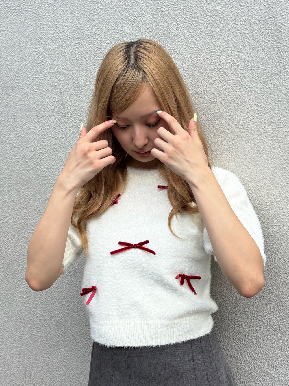 グレー系のスカート、ホワイト系のニット/セーター、ブラウン系のブーツを着用したレディースの秋コーディネートの4枚目の写真