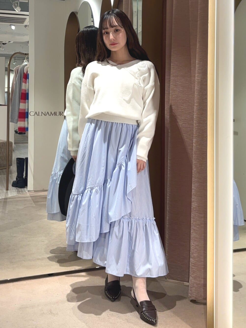 ブラウン系のサンダル、ホワイト系のニット/セーター、ブルー系のスカートを着用したレディースの春コーディネートの5枚目の写真