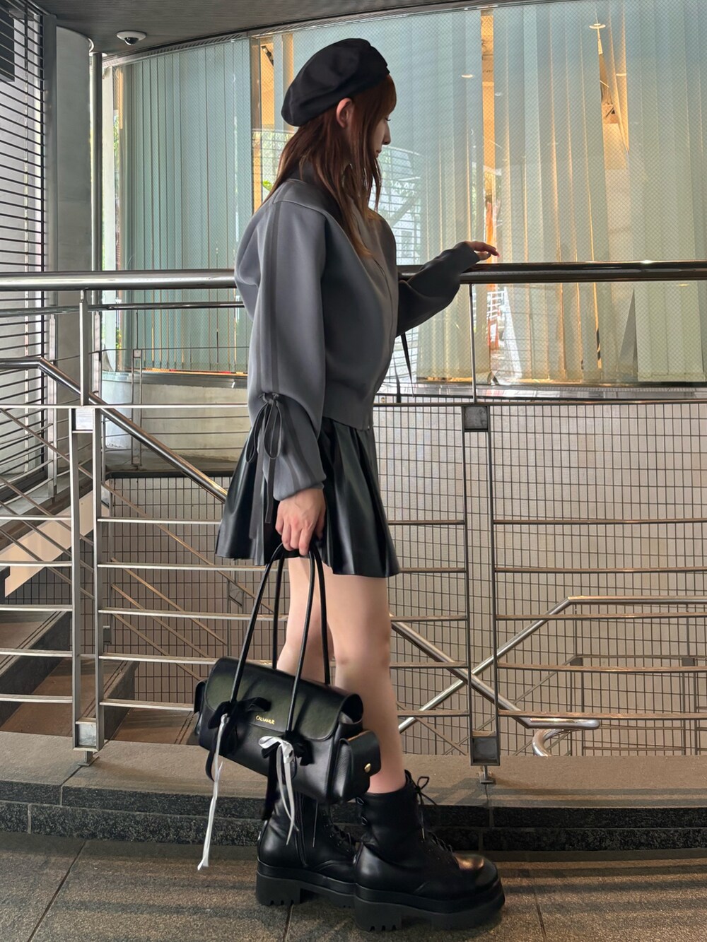 グレー系のブルゾン、ブラック系のハンドバッグ、ブラック系のブーツを着用したレディースの夏コーディネートの5枚目の写真