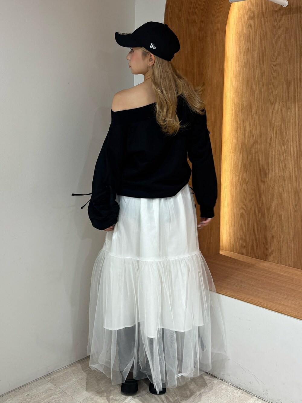 ホワイト系のスカート、ブラック系のスウェット、ブラウン系のブーツを着用したレディースの秋コーディネートの3枚目の写真