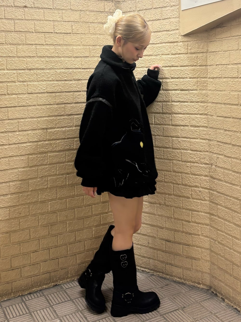 ブラック系のスウェット、ブラック系のスカート、ブラウン系のブーツを着用したレディースの秋コーディネートの2枚目の写真