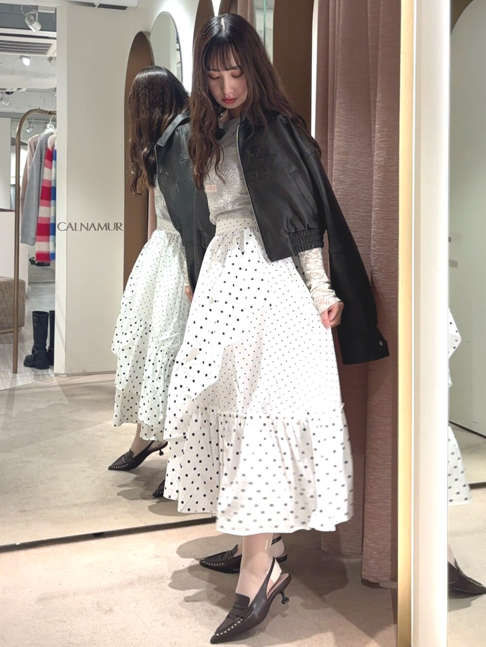 ブラウン系のブルゾン、ホワイト系のスカート、ブラウン系のサンダルを着用したレディースの春コーディネートの2枚目の写真