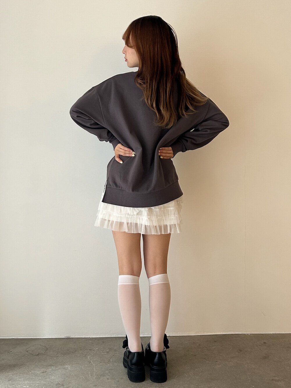 グレー系のスウェット、ホワイト系のローファー、ホワイト系のスカートを着用したレディースの秋コーディネートの2枚目の写真