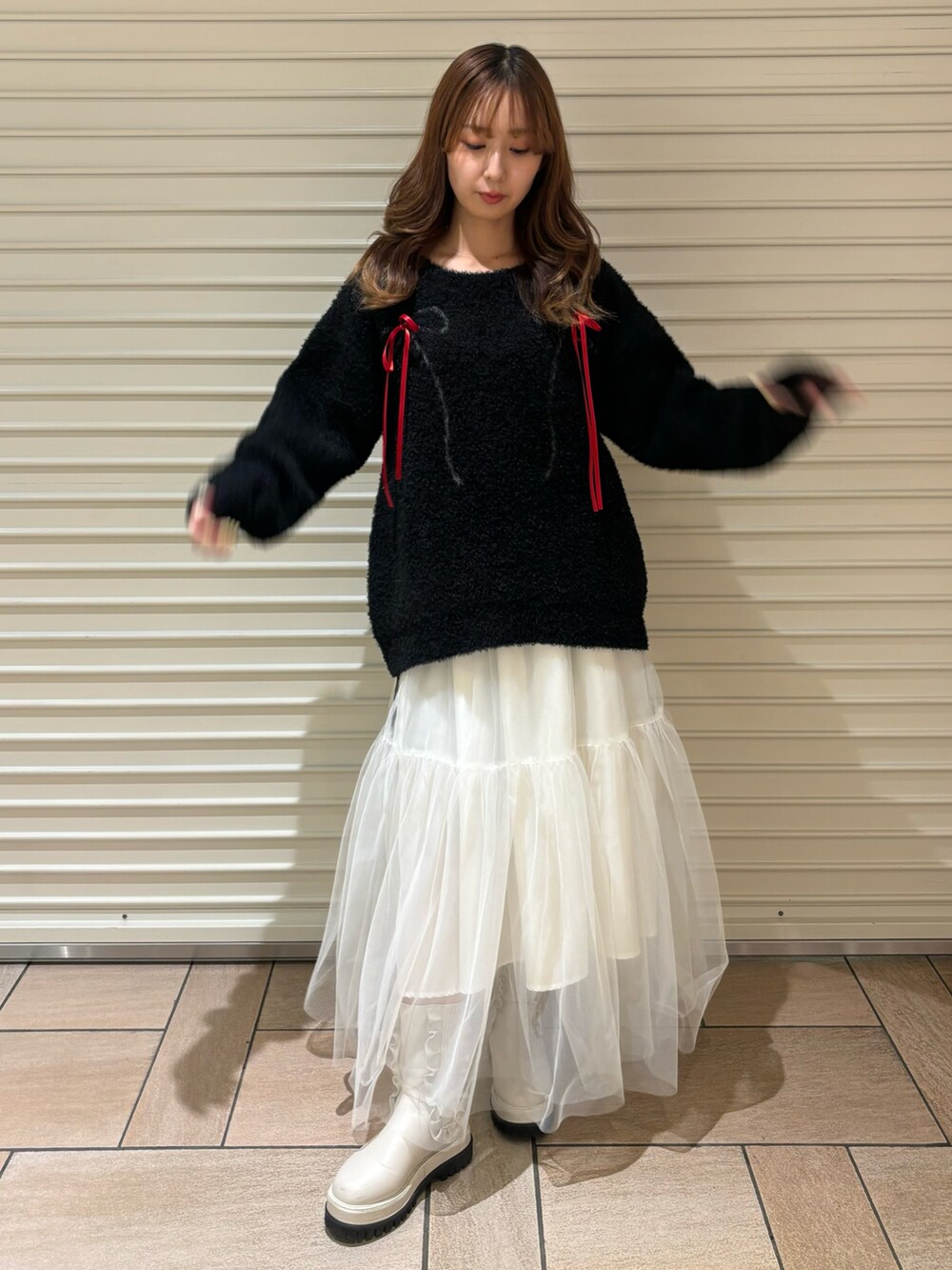 ブラック系のニット/セーター、ホワイト系のスカート、ホワイト系のブーツを着用したレディースの秋コーディネートの2枚目の写真