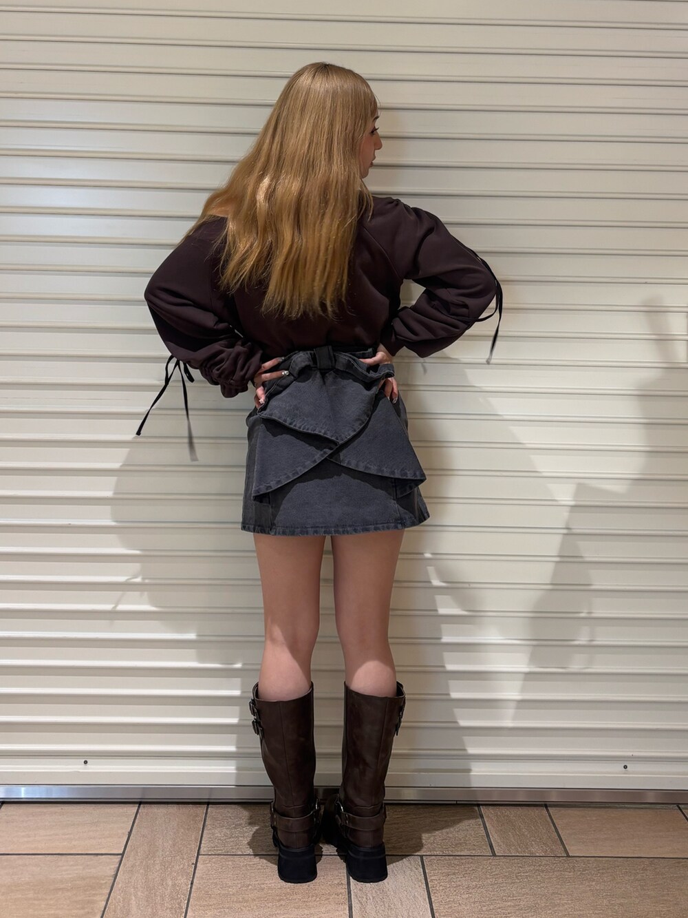 ブラック系のデニムスカート、ブラウン系のスウェット、ブラウン系のブーツを着用したレディースの秋コーディネートの3枚目の写真