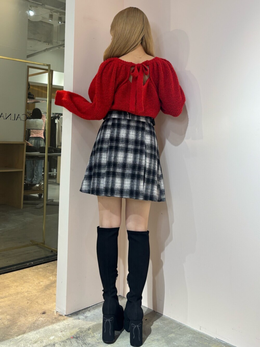 ブラック系のブーツ、レッド系のニット/セーター、その他のスカートを着用したレディースの秋コーディネートの3枚目の写真