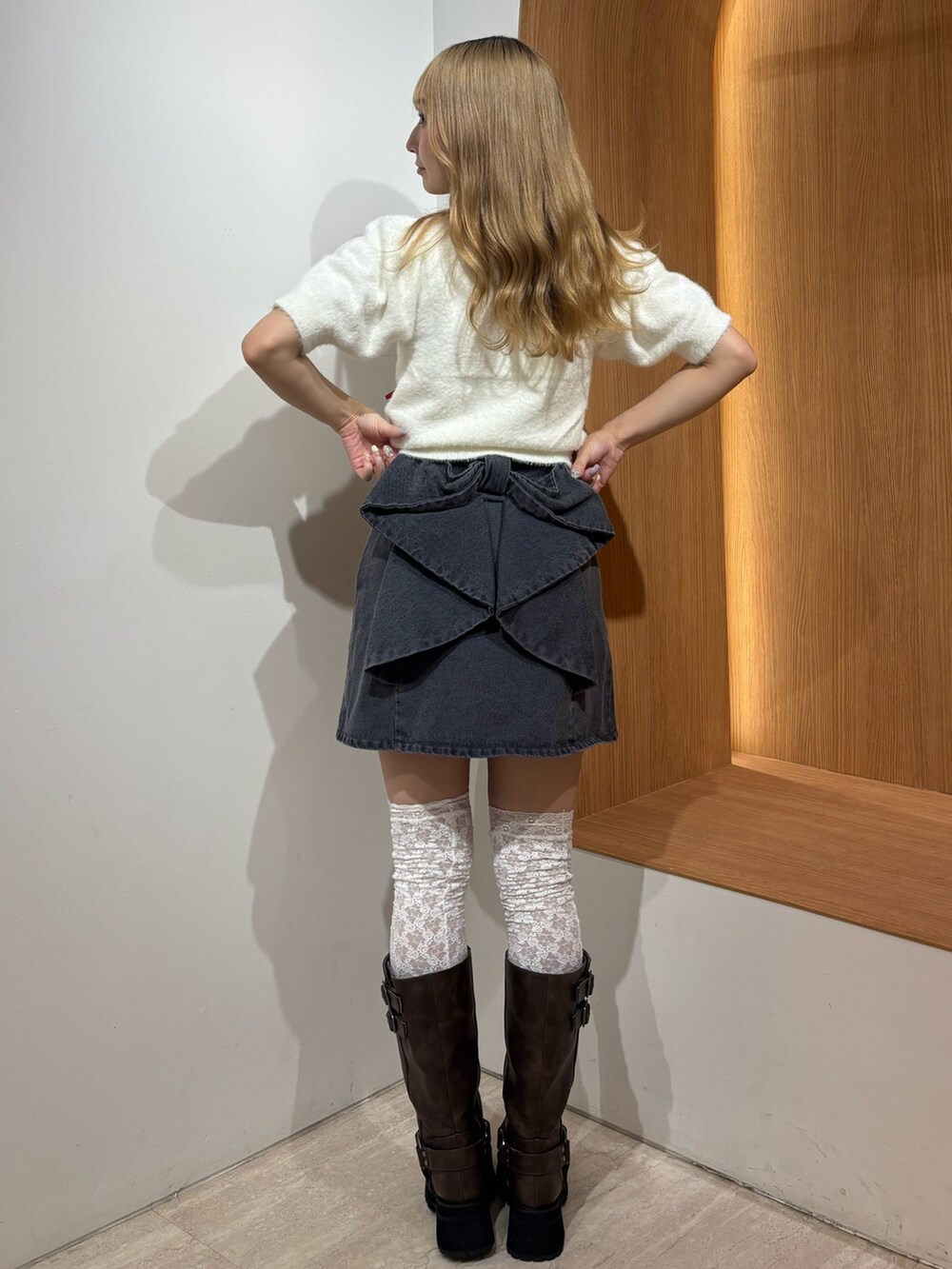 ブラック系のデニムスカート、ホワイト系のニット/セーター、ブラウン系のブーツを着用したレディースの秋コーディネートの3枚目の写真