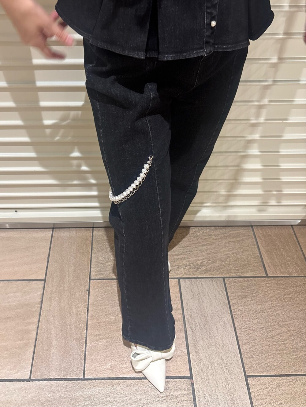 ブラック系のキャミソール、ブラック系のデニムパンツ、ホワイト系のサンダルを着用したレディースの夏コーディネートの5枚目の写真