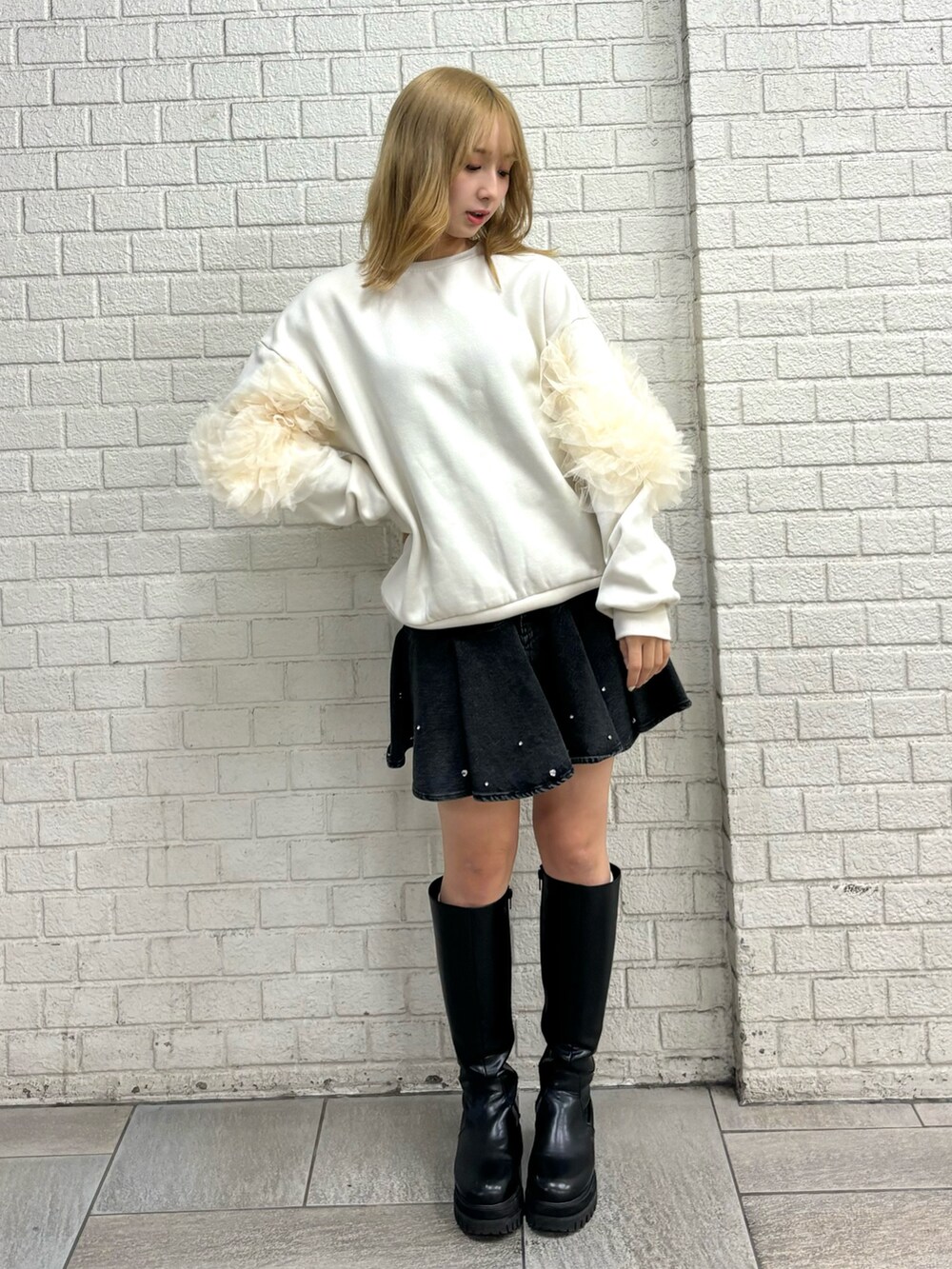 ホワイト系のスウェット、ブラック系のブーツ、ブルー系のスカートを着用したレディースの秋コーディネートの6枚目の写真