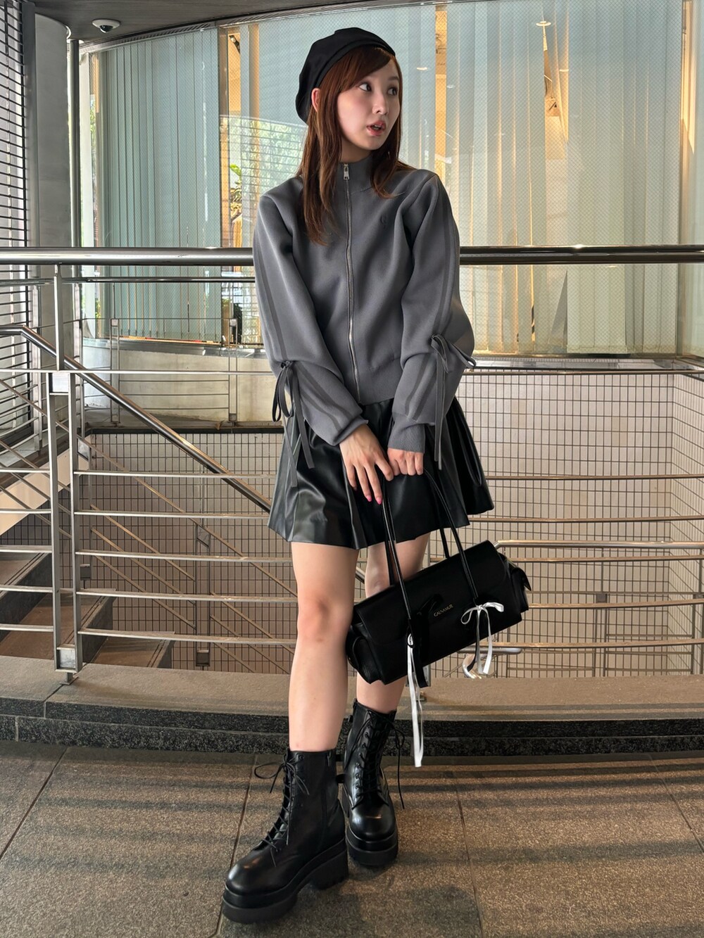 グレー系のブルゾン、ブラック系のハンドバッグ、ブラック系のブーツを着用したレディースの夏コーディネートの2枚目の写真