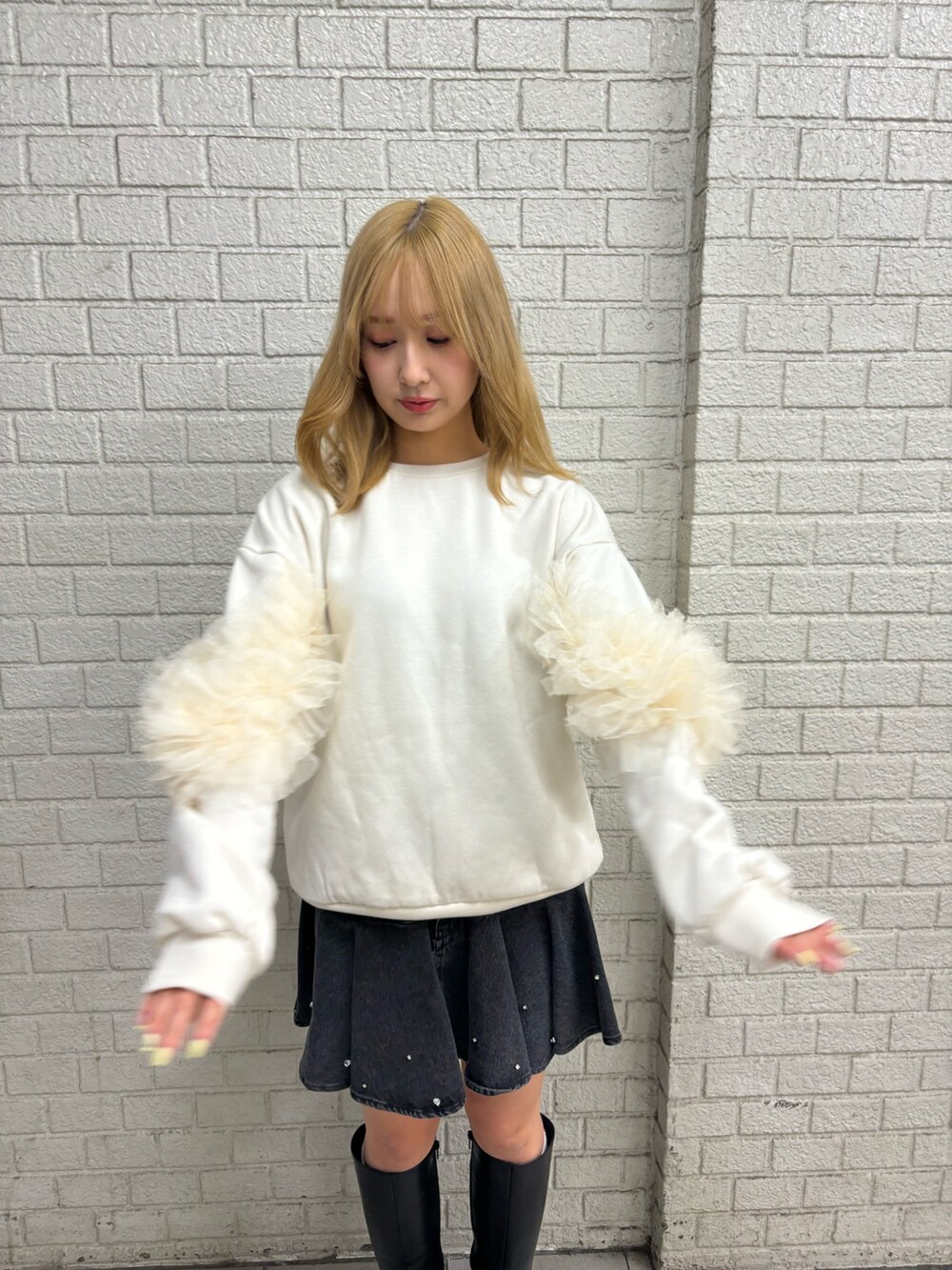 ホワイト系のスウェット、ブラック系のブーツ、ブルー系のスカートを着用したレディースの秋コーディネートの7枚目の写真