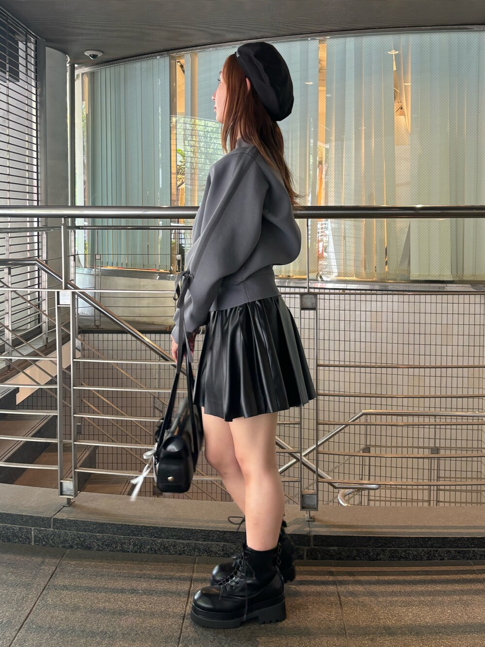 グレー系のブルゾン、ブラック系のハンドバッグ、ブラック系のブーツを着用したレディースの夏コーディネートの3枚目の写真