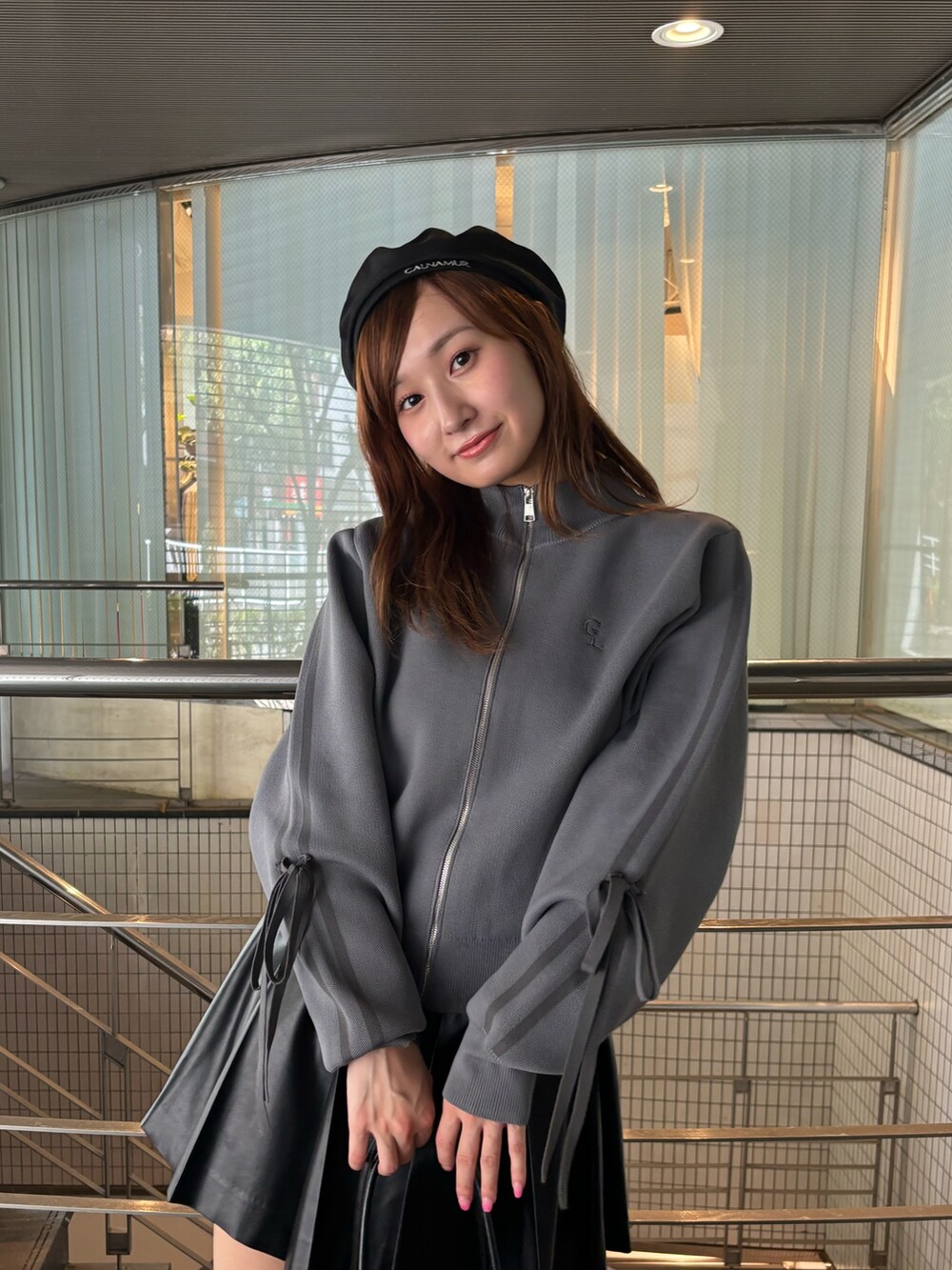 グレー系のブルゾン、ブラック系のハンドバッグ、ブラック系のブーツを着用したレディースの夏コーディネートの6枚目の写真