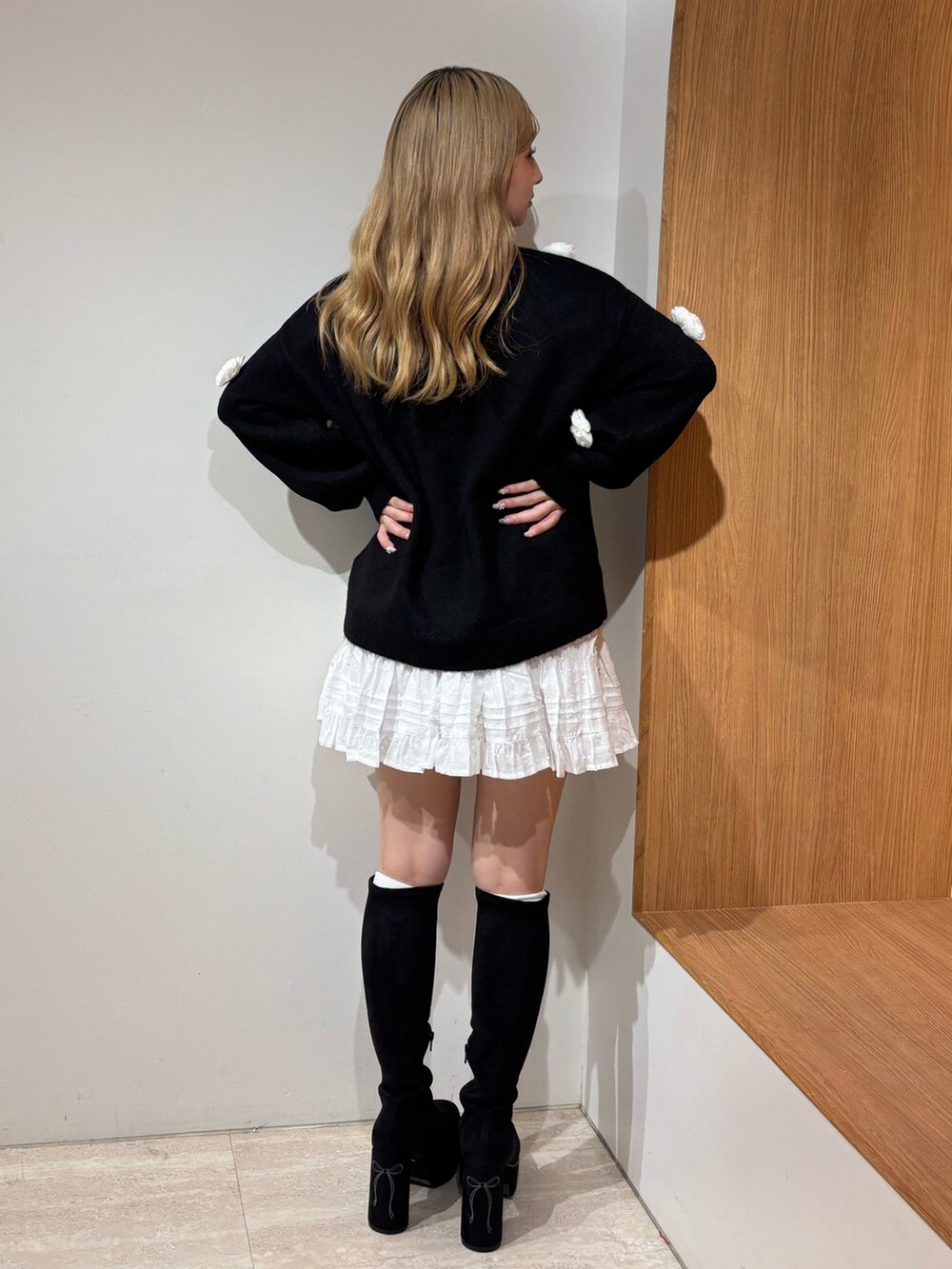 ホワイト系のスカート、ブラック系のニット/セーター、ブラック系のブーツを着用したレディースの秋コーディネートの3枚目の写真