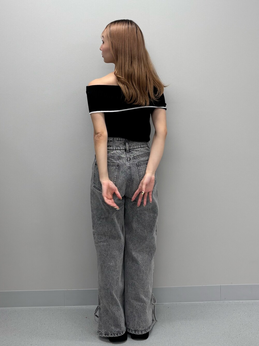 ブルー系のデニムパンツ、ブラック系のニット/セーター、ホワイト系のサンダルを着用したレディースの春コーディネートの3枚目の写真
