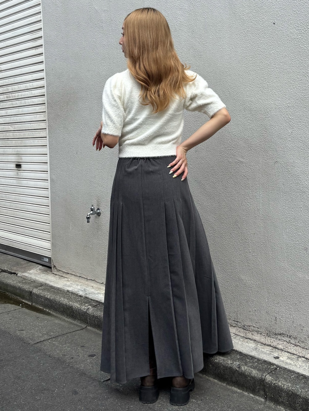 グレー系のスカート、ホワイト系のニット/セーター、ブラウン系のブーツを着用したレディースの秋コーディネートの3枚目の写真