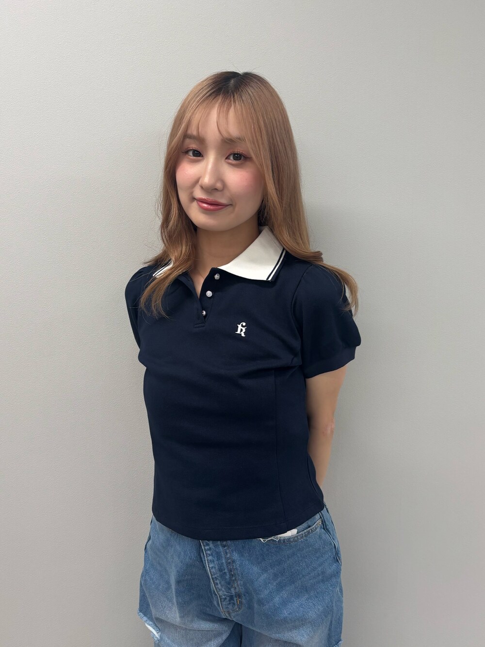 ブルー系のデニムパンツ、ブルー系のポロシャツ、ホワイト系のサンダルを着用したレディースの春コーディネートの5枚目の写真