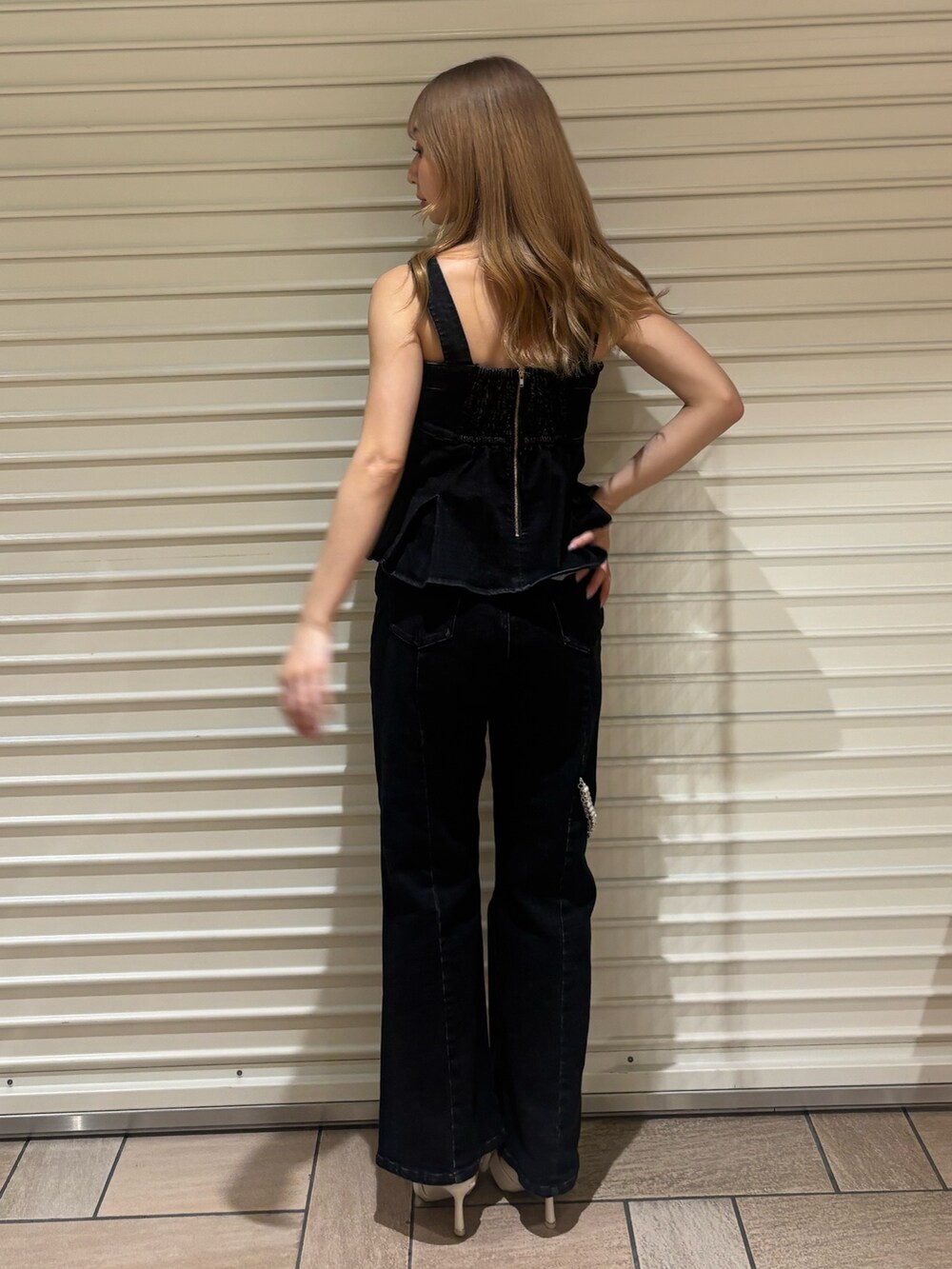 ブラック系のキャミソール、ブラック系のデニムパンツ、ホワイト系のサンダルを着用したレディースの夏コーディネートの3枚目の写真