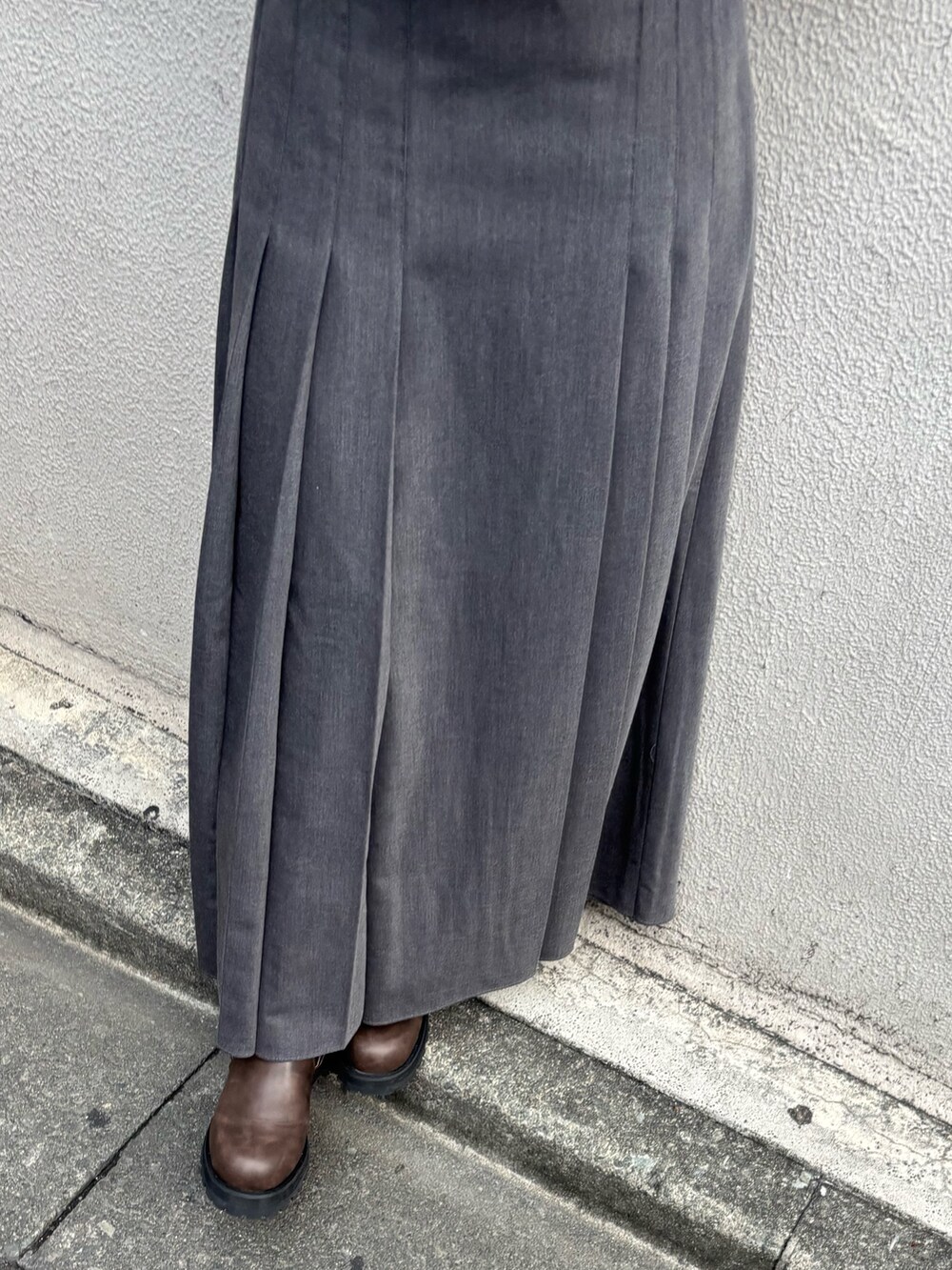 グレー系のスカート、ホワイト系のニット/セーター、ブラウン系のブーツを着用したレディースの秋コーディネートの5枚目の写真