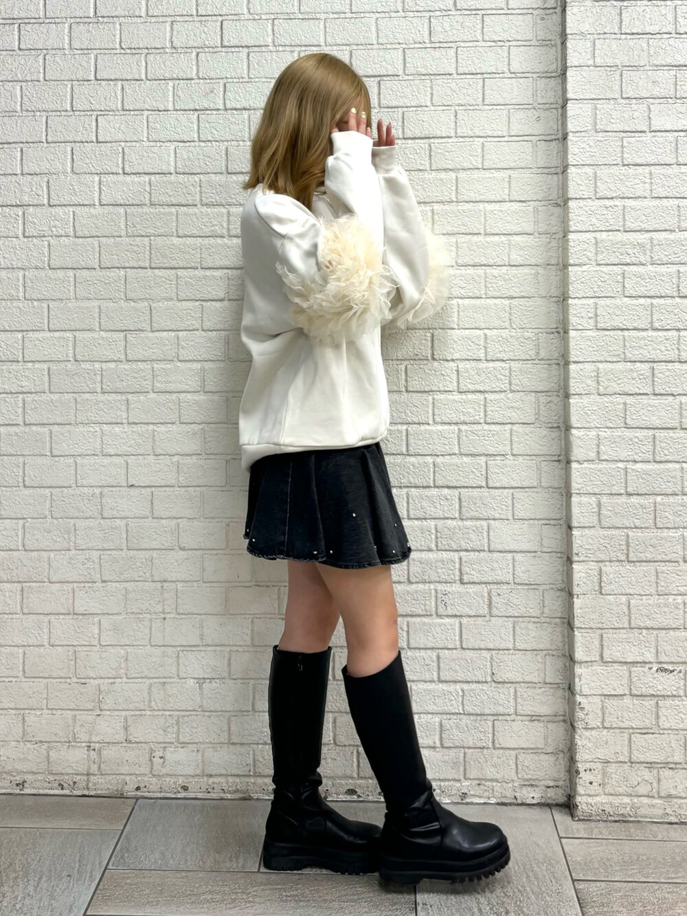 ホワイト系のスウェット、ブラック系のブーツ、ブルー系のスカートを着用したレディースの秋コーディネートの5枚目の写真