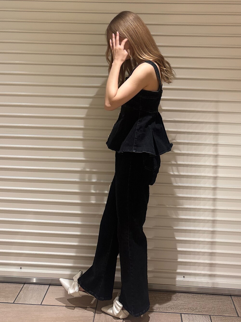 ブラック系のキャミソール、ブラック系のデニムパンツ、ホワイト系のサンダルを着用したレディースの夏コーディネートの2枚目の写真