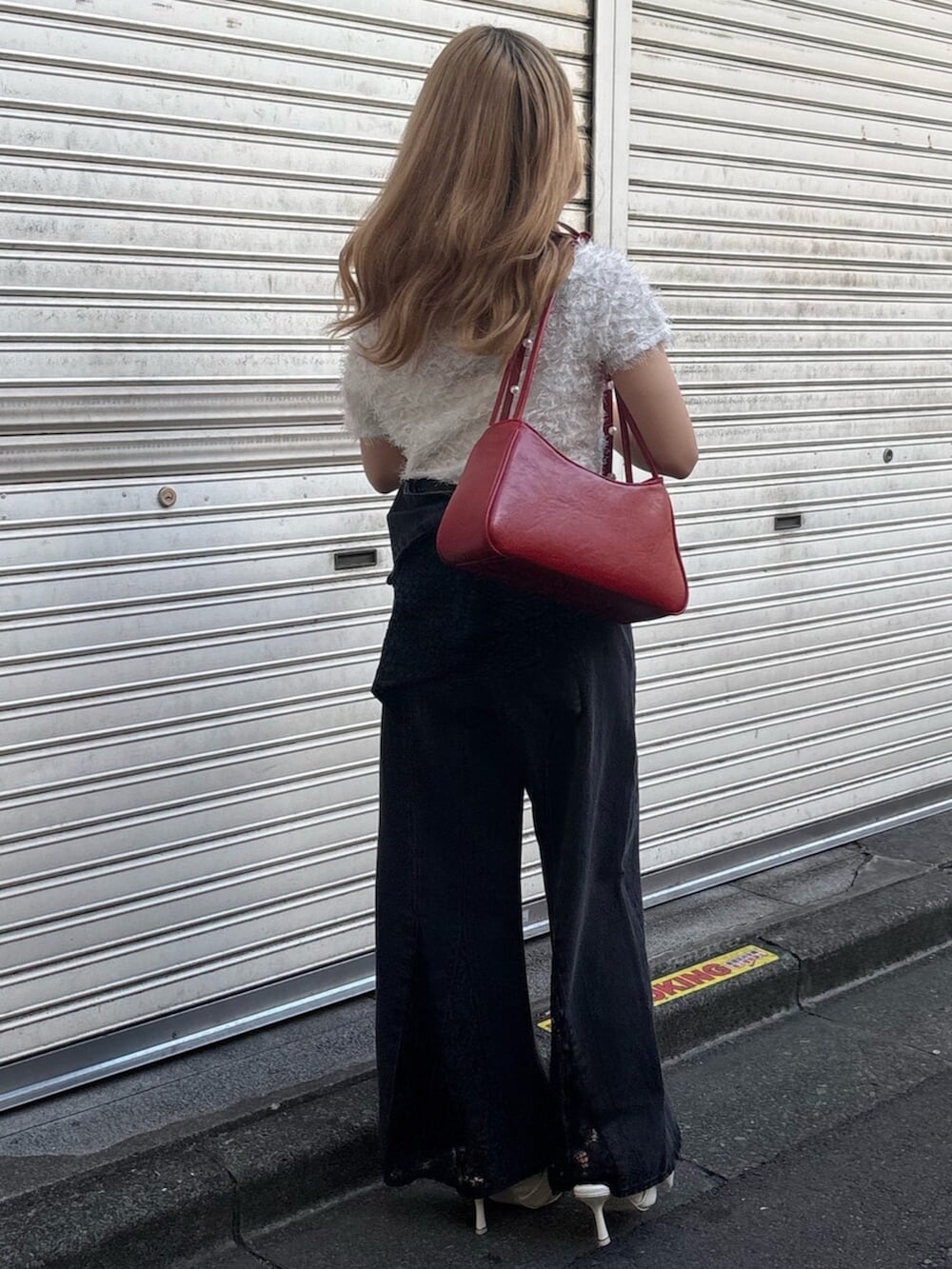 ホワイト系のサンダル、レッド系のハンドバッグ、ブラック系のデニムパンツを着用したレディースの夏コーディネートの3枚目の写真