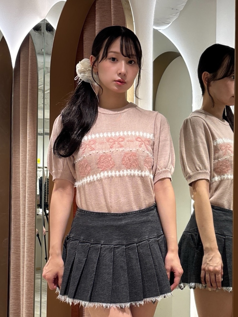 ブラック系のスカート、ピンク系のニット/セーター、ブラック系のブーツを着用したレディースの秋コーディネートの5枚目の写真