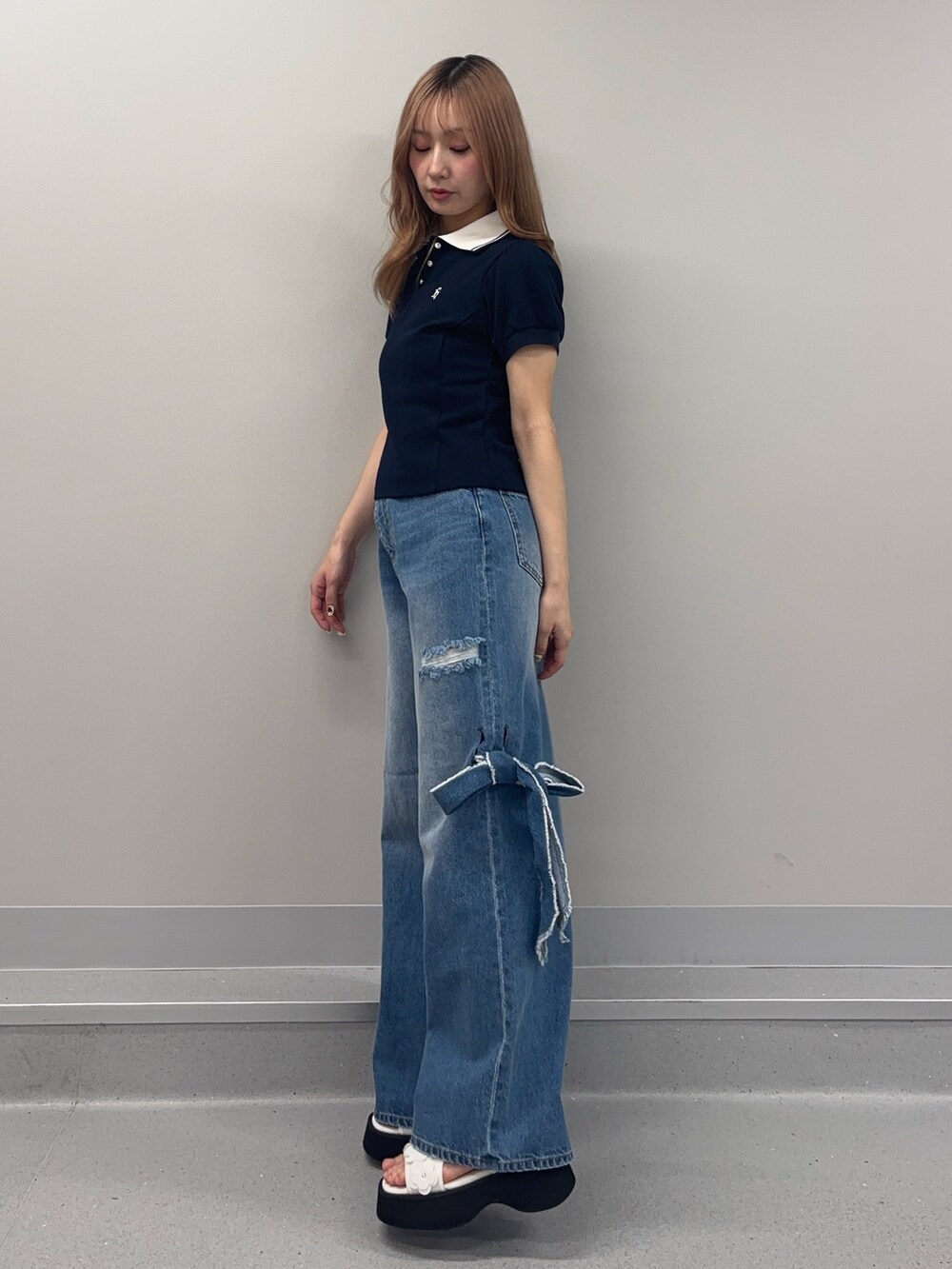ブルー系のデニムパンツ、ブルー系のポロシャツ、ホワイト系のサンダルを着用したレディースの春コーディネートの4枚目の写真