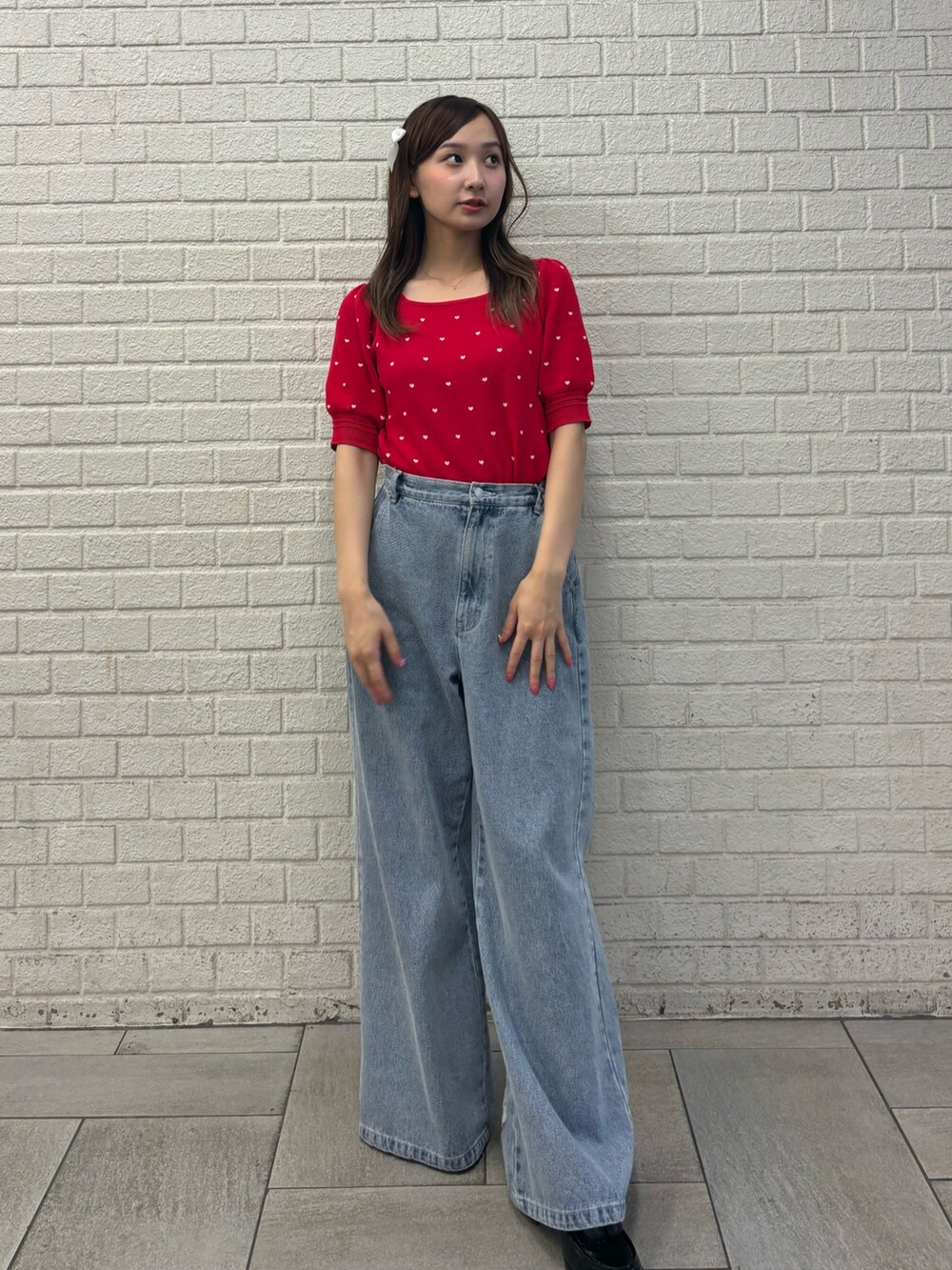 ブルー系のデニムパンツ、レッド系のニット/セーター、ブラック系のバレッタ/ヘアクリップを着用したレディースの夏コーディネートの2枚目の写真