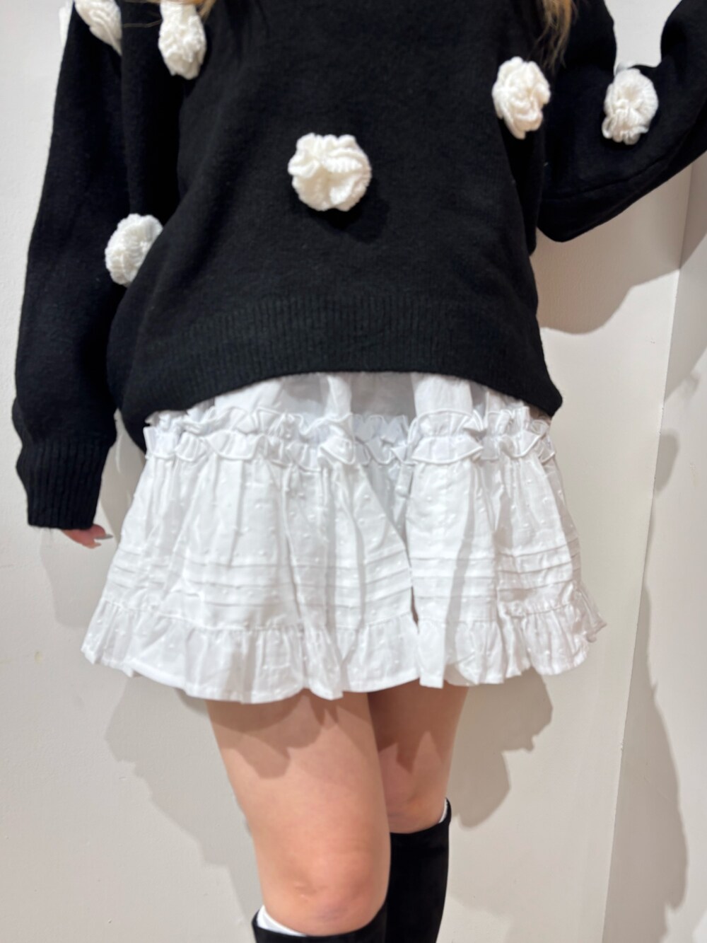 ホワイト系のスカート、ブラック系のニット/セーター、ブラック系のブーツを着用したレディースの秋コーディネートの5枚目の写真