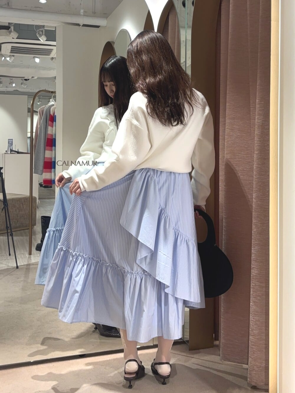 ブラウン系のサンダル、ホワイト系のニット/セーター、ブルー系のスカートを着用したレディースの春コーディネートの3枚目の写真