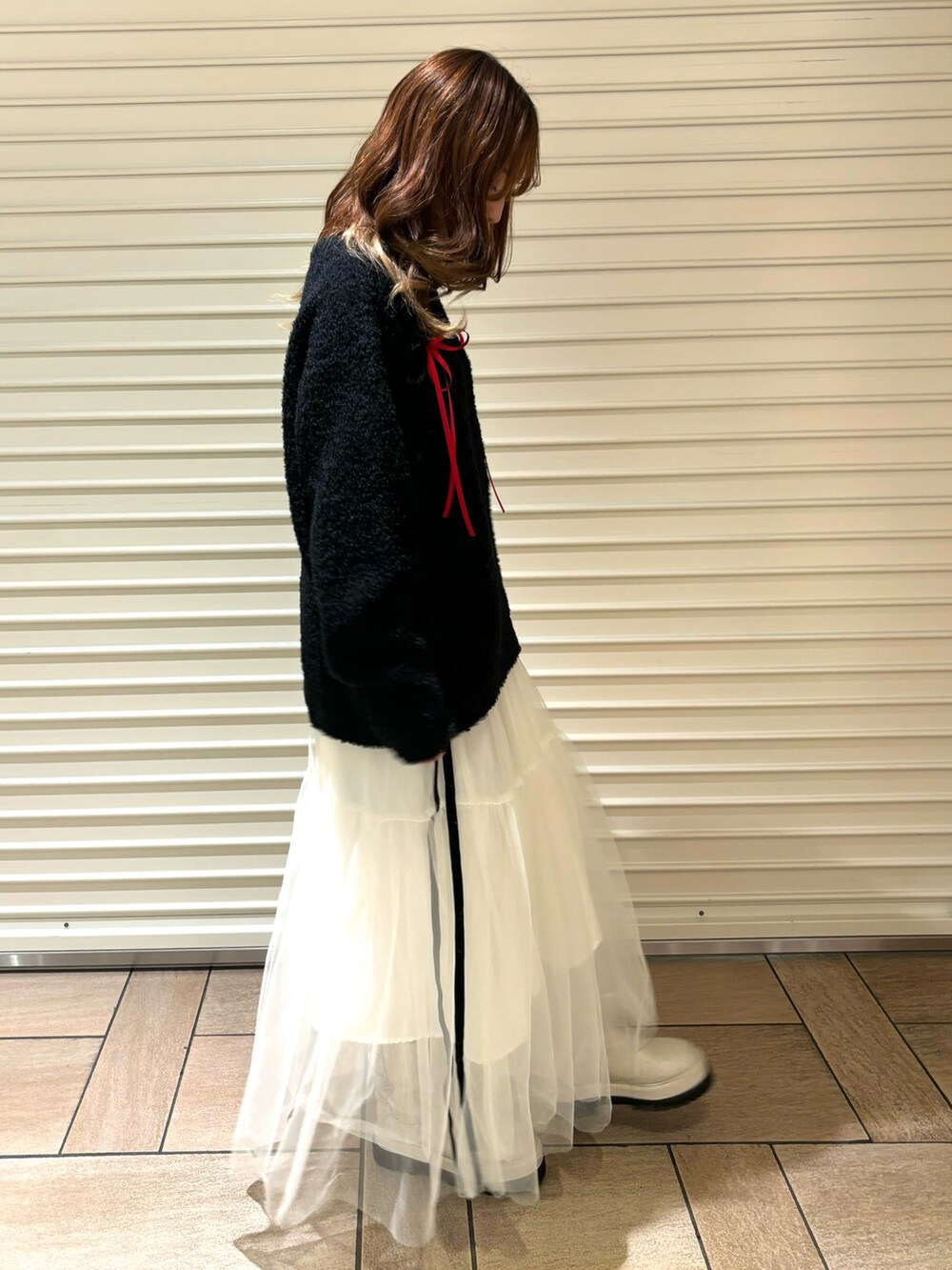 ブラック系のニット/セーター、ホワイト系のスカート、ホワイト系のブーツを着用したレディースの秋コーディネートの3枚目の写真