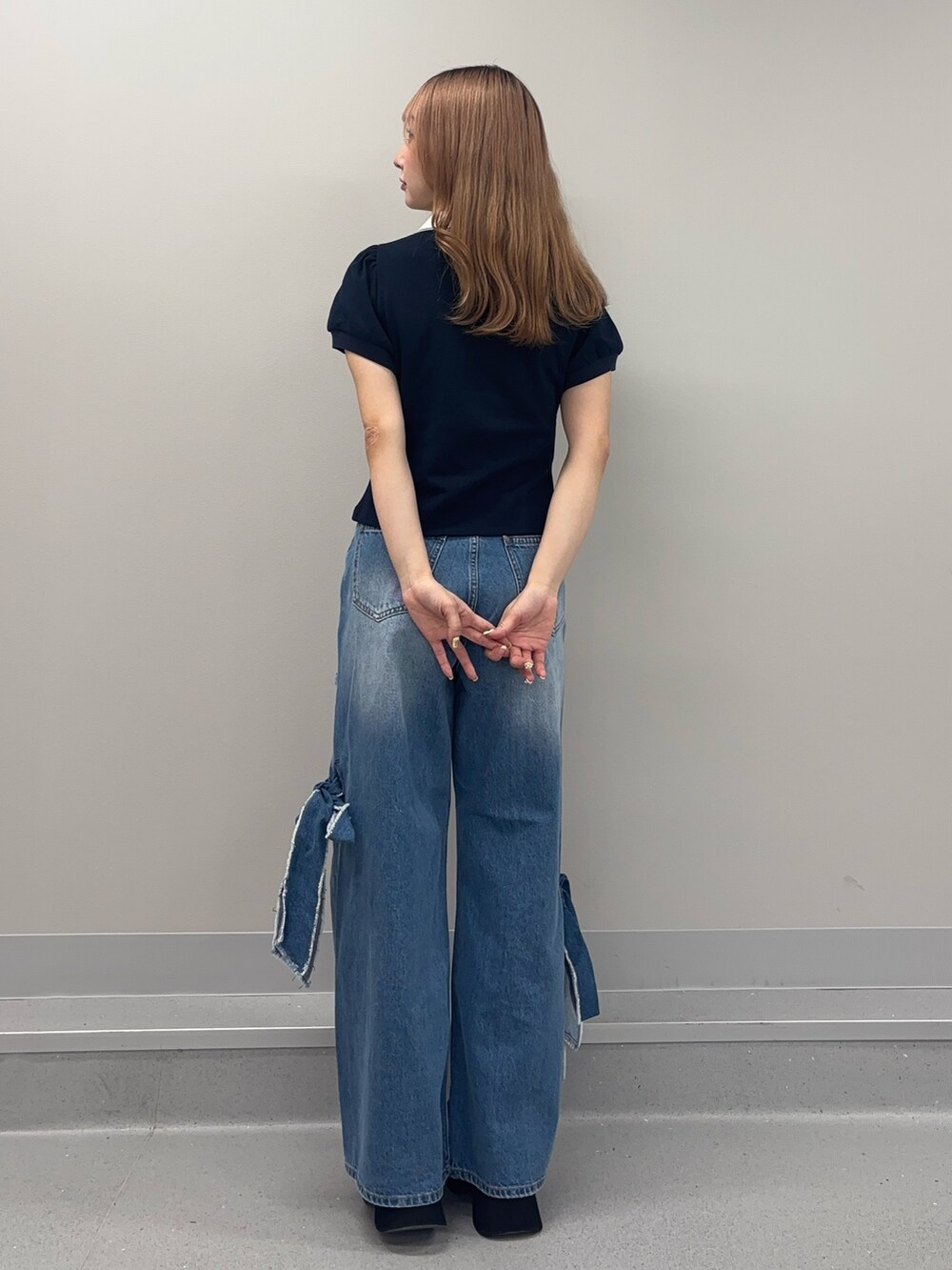 ブルー系のデニムパンツ、ブルー系のポロシャツ、ホワイト系のサンダルを着用したレディースの春コーディネートの3枚目の写真