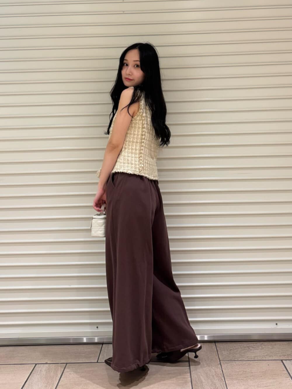 ブラウン系のサンダル、ブラウン系のスウェットパンツ、ベージュ系のベストを着用したレディースの夏コーディネートの5枚目の写真