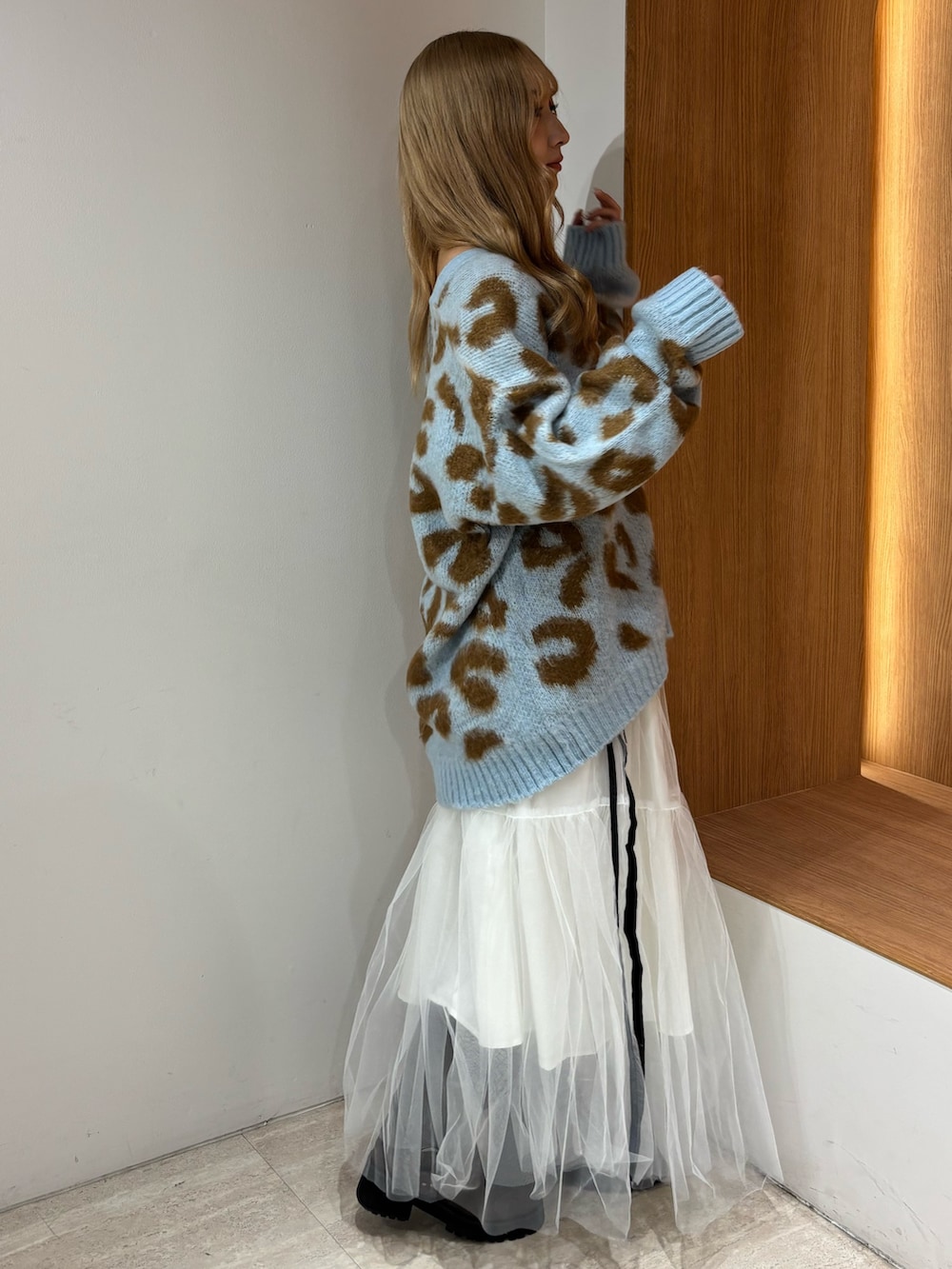 ブルー系のニット/セーター、ホワイト系のスカート、ブラウン系のブーツを着用したレディースの秋コーディネートの2枚目の写真