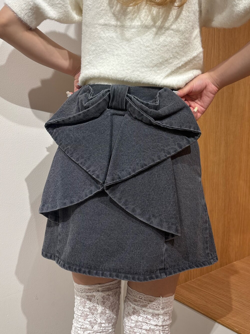 ブラック系のデニムスカート、ホワイト系のニット/セーター、ブラウン系のブーツを着用したレディースの秋コーディネートの4枚目の写真